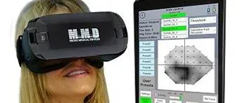 A woman wears a black virtual reality headset labeled M.A.D. next to a tablet screen displaying a medical visual field test with a grid and various control options.